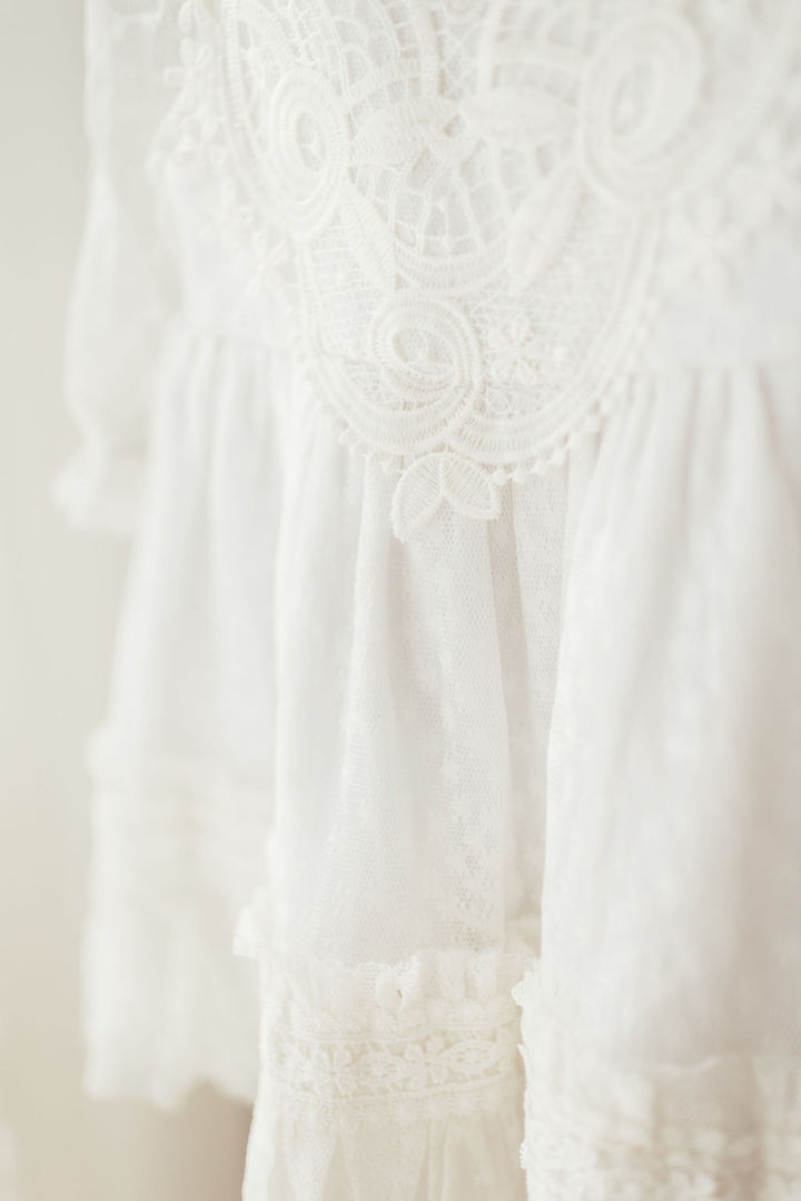 A close-up view of a delicate, white lace dress with intricate patterns and designs.