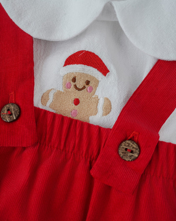 A red dress with a white collar and a red and white embroidered gingerbread man figure on the front.
