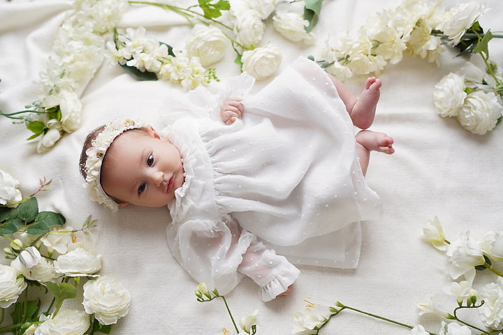 a baby doll laying on a bed of flowers