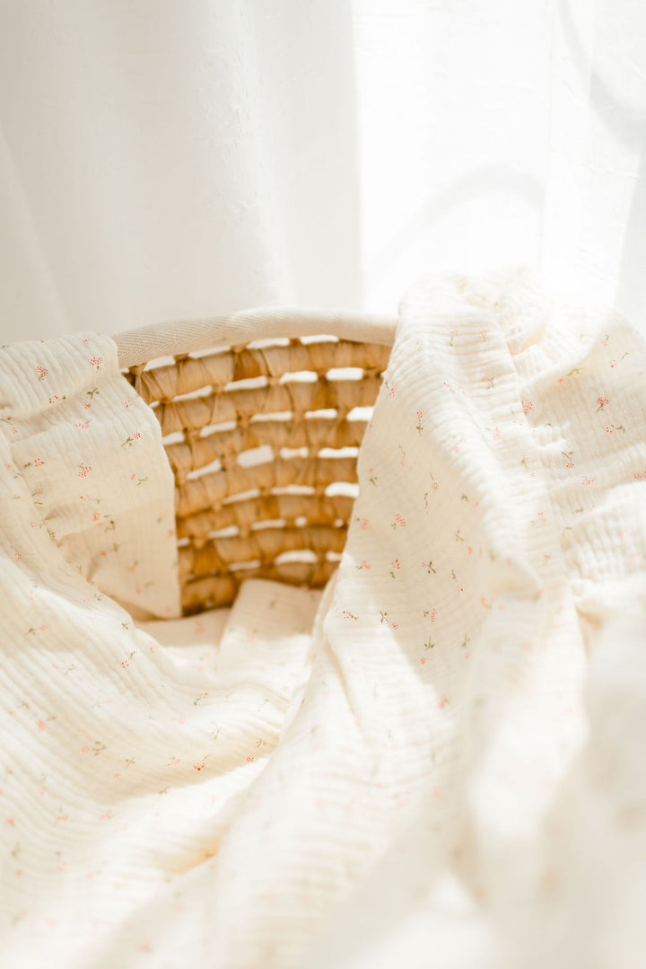 A woven basket with a white cloth draped over it, placed against a white background.