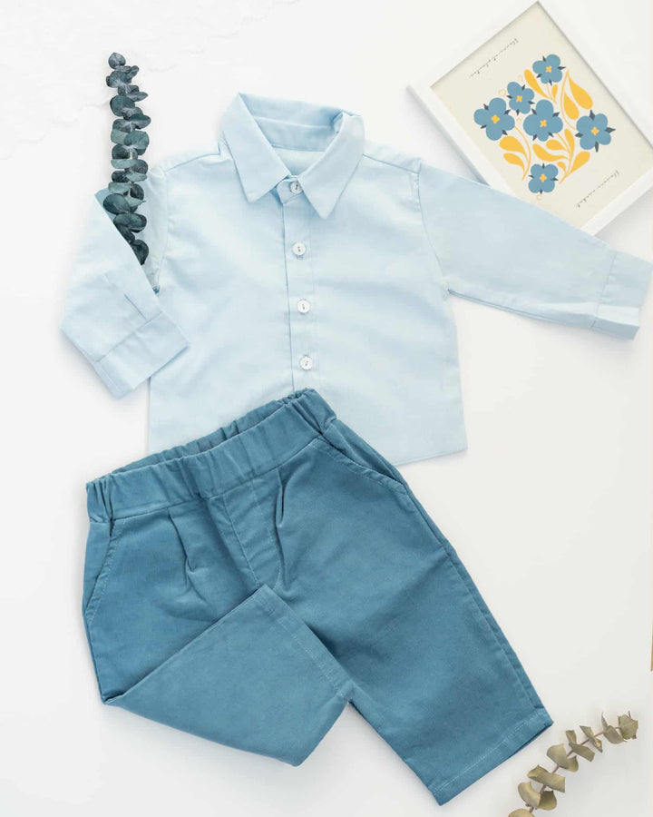 a light blue collared shirt and blue pants arranged on a white background.