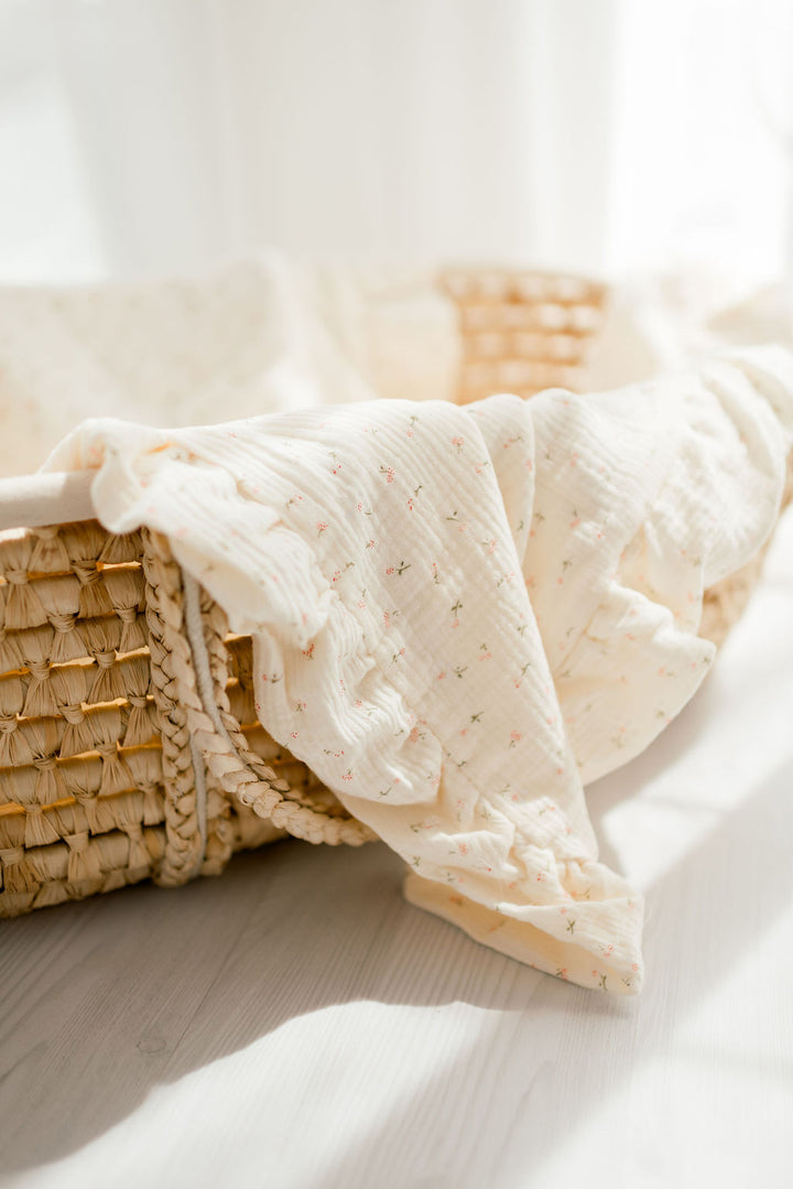A woven basket with a white cloth draped over it, placed on a wooden surface.