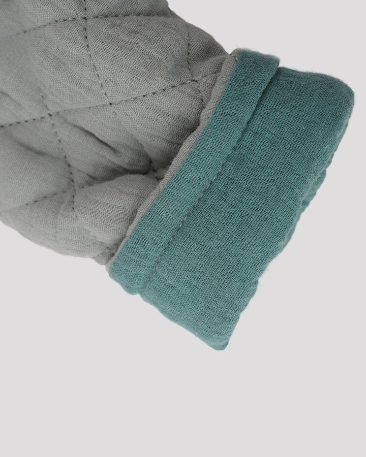 A close-up view of a gray and teal quilted glove against a plain white background.
