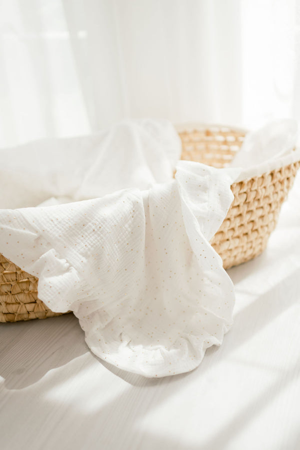 A woven basket with a white cloth draped over it, placed on a white surface.