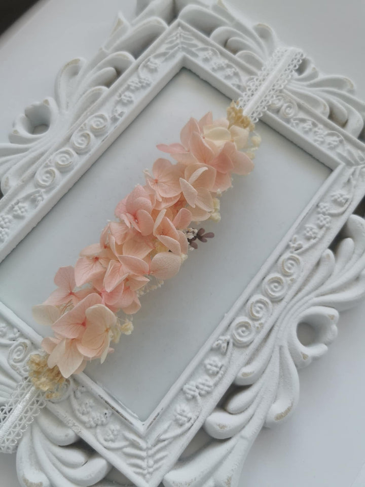 A delicate floral arrangement of pink and white flowers is displayed in an ornate white frame.
