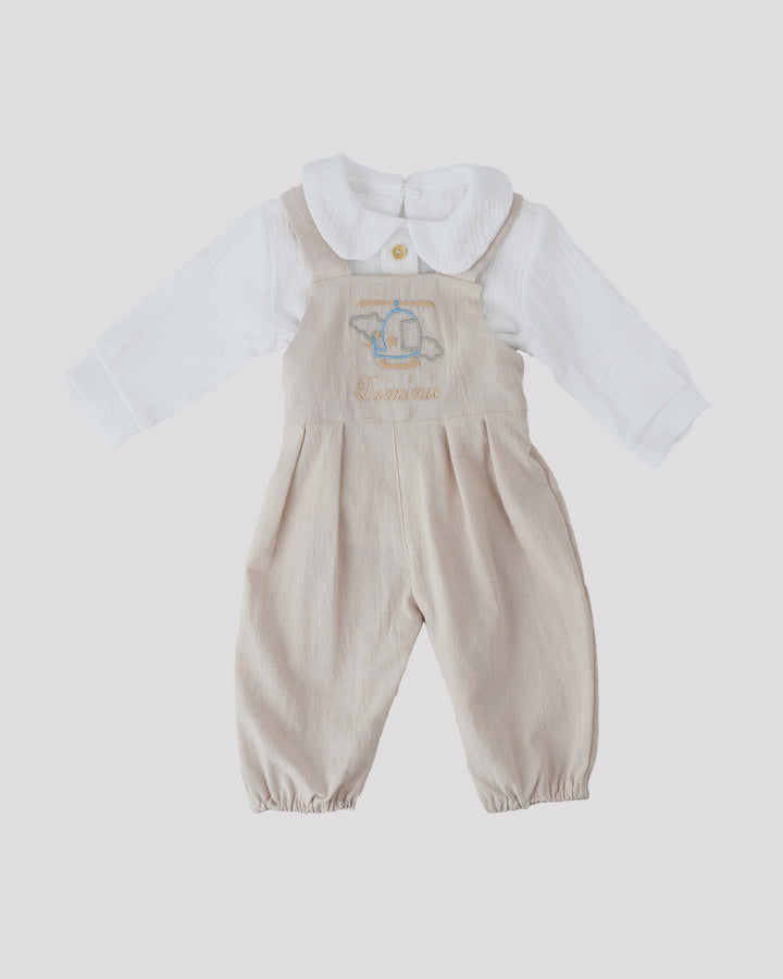 A beige onesie with a white collar and a white shirt underneath, featuring a blue and white embroidered design on the front.