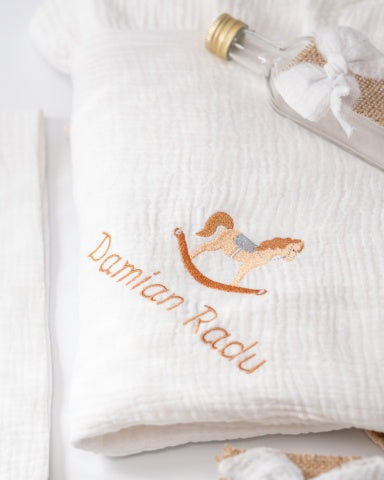 a white towel with an embroidered image of a rocking horse and the name "Damian Radu" written on it.