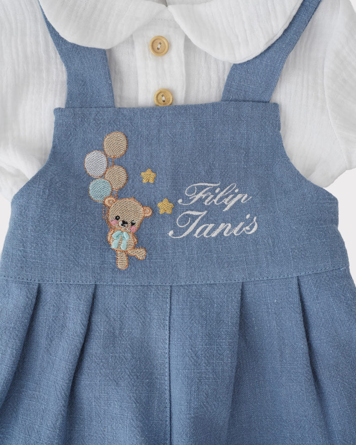 A blue denim dress with a teddy bear embroidered on it, and the name 'Felip Tanis' written on the front.