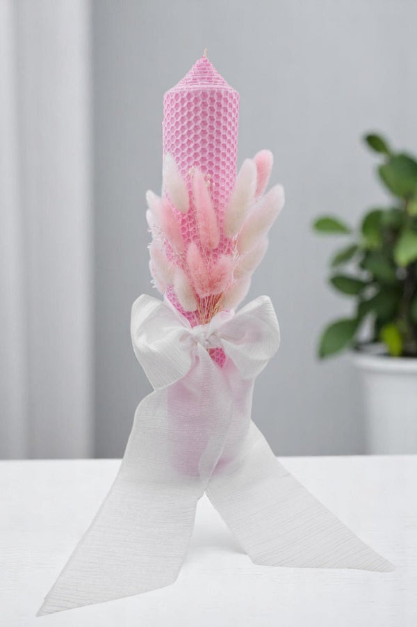 a pink candle with a white ribbon around it