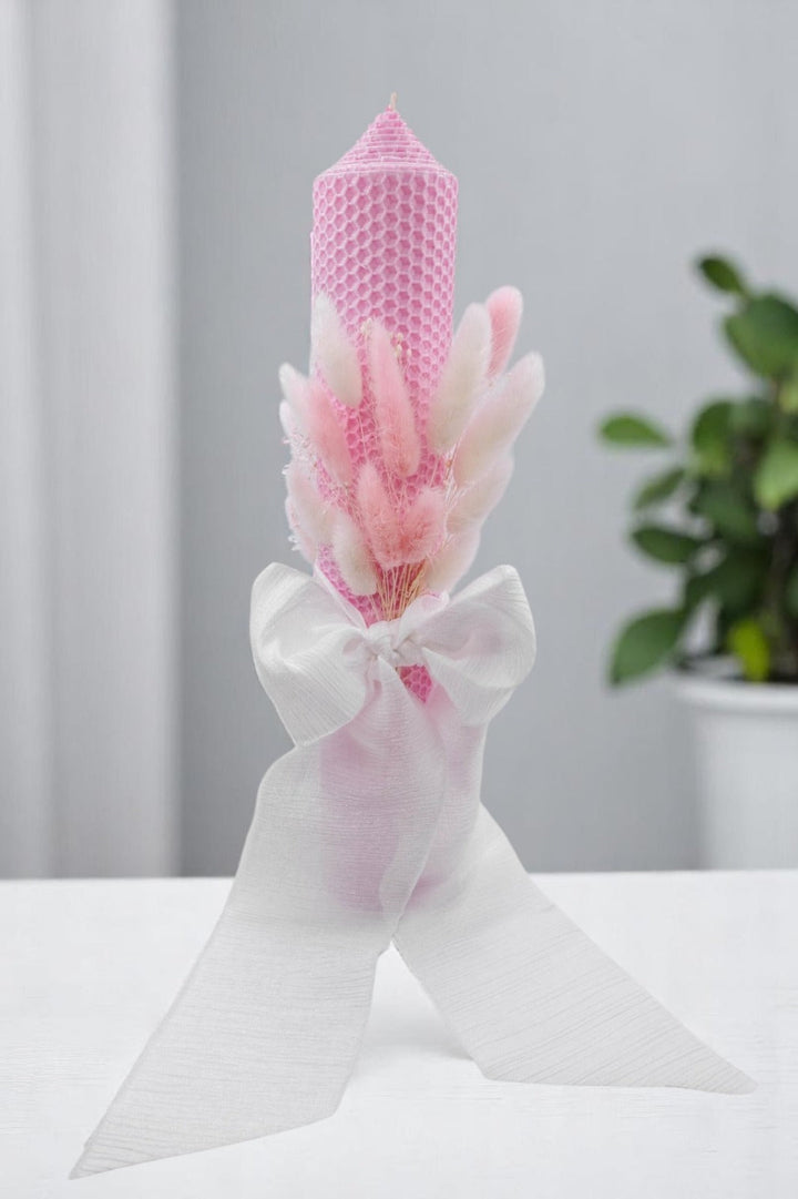 a pink candle with a white ribbon around it