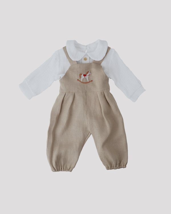 A beige onesie with a white collar and a white shirt with a red and white embroidered image of a rocking horse on the front.