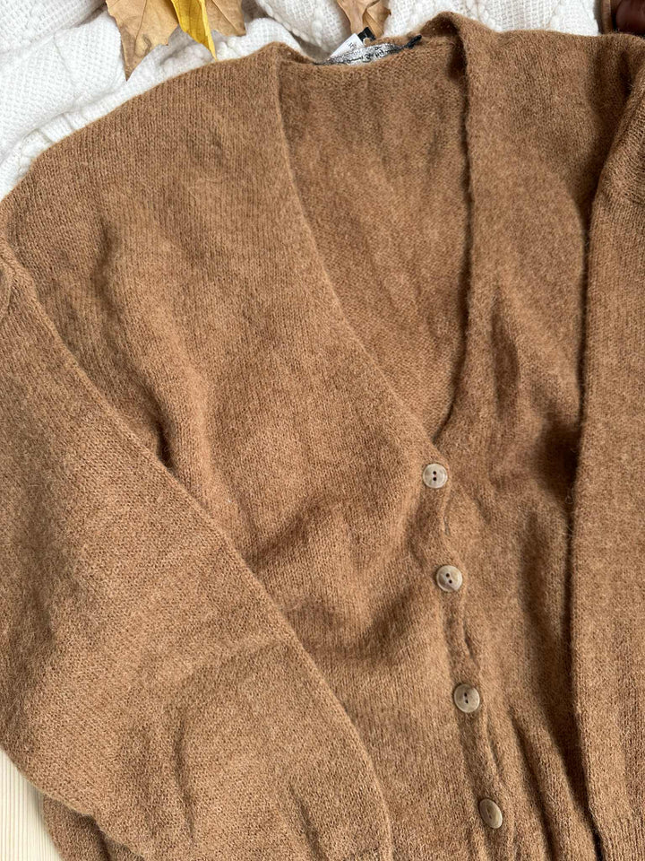 A brown cardigan with buttons and long sleeves is shown in the image.