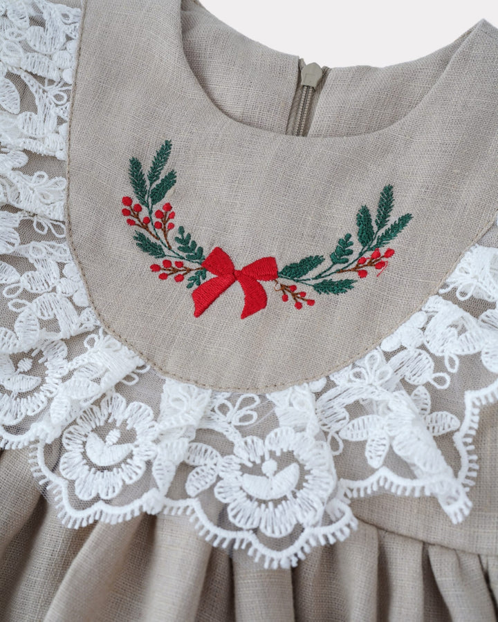 a close-up view of a beige dress with a lace collar and a red bow on the front. The dress has a delicate lace trim and a floral embroidered design on the neckline.