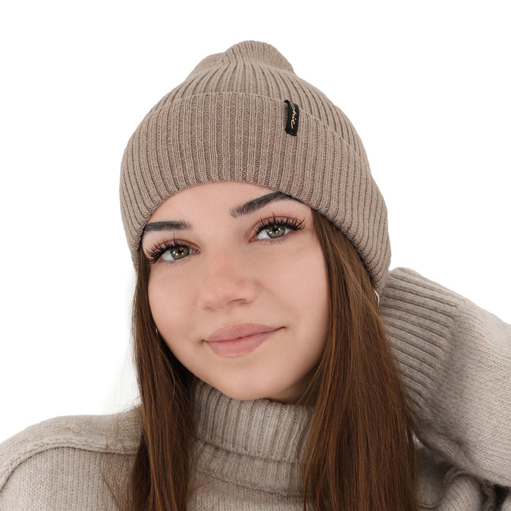 A woman wearing a beige knit hat and a beige sweater, smiling at the camera.