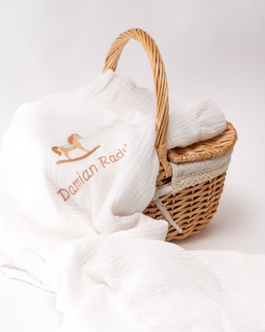 a wicker basket with a white blanket and a white towel