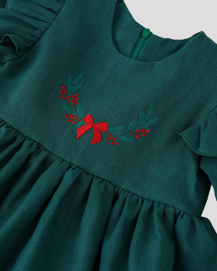A green dress with a red bow and green leaves embroidered on it.