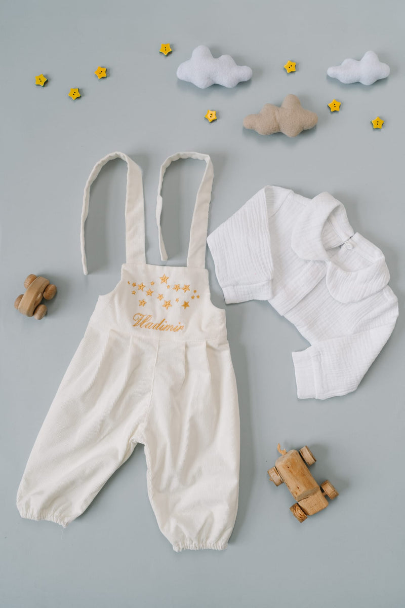 a collection of baby clothing and toys arranged on a light blue background.