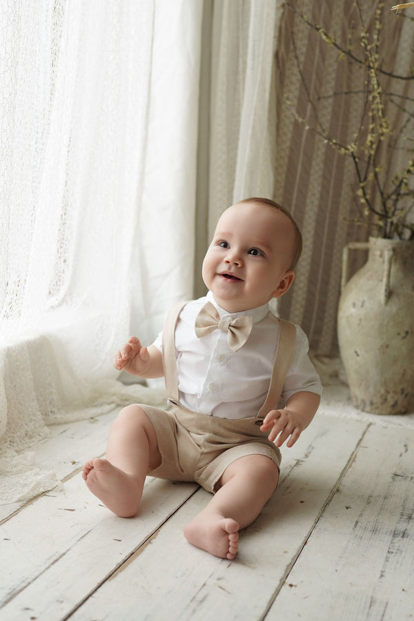 a baby sitting on the floor wearing a bow tie