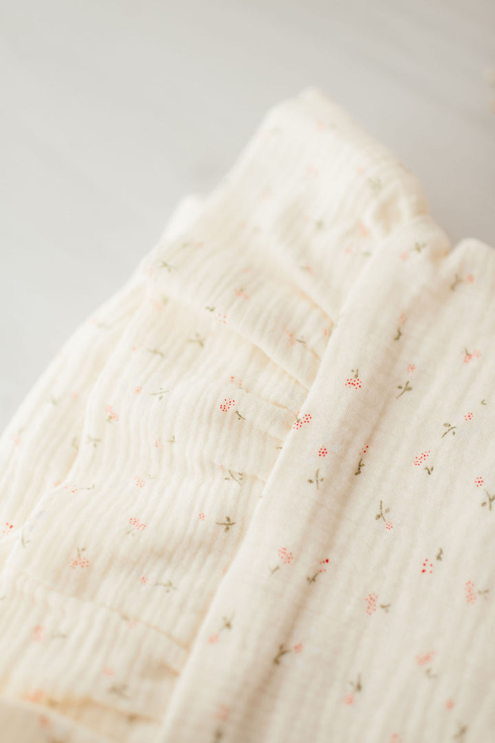 a close-up view of a white fabric with a floral pattern, featuring small red flowers on a white background.