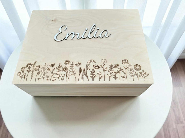 A wooden box with the name "Emilia" engraved on it, featuring a floral design.