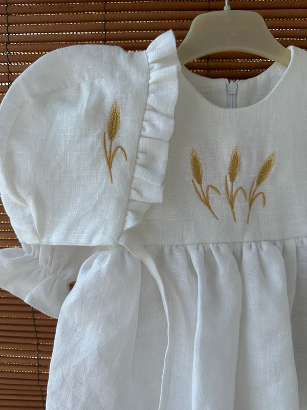 A white dress with gold embroidered wheat stalks on the front.