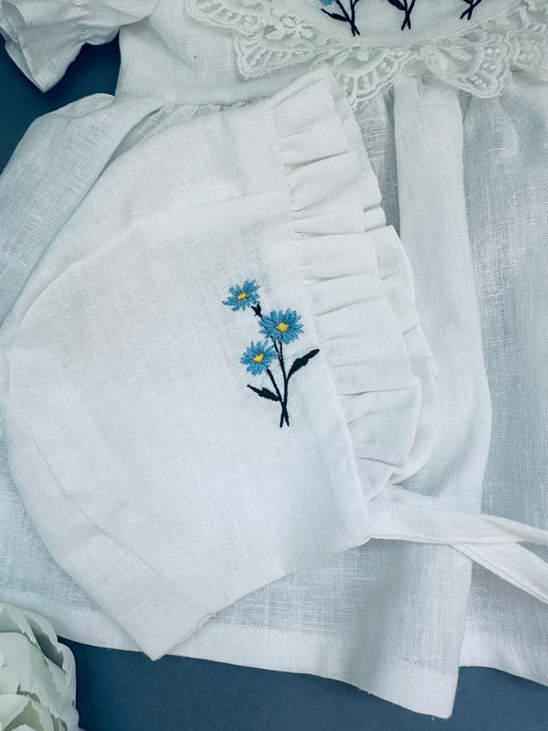 A white cloth with a blue flower embroidered on it, along with a white lace trim.