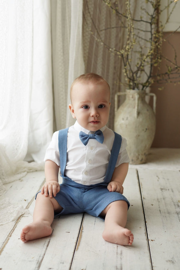 a baby sitting on the floor wearing a blue bow tie
