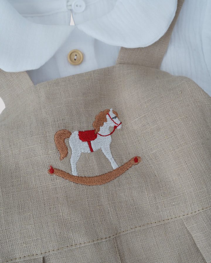 A close-up view of a beige fabric with a red and white embroidered image of a rocking horse on it.