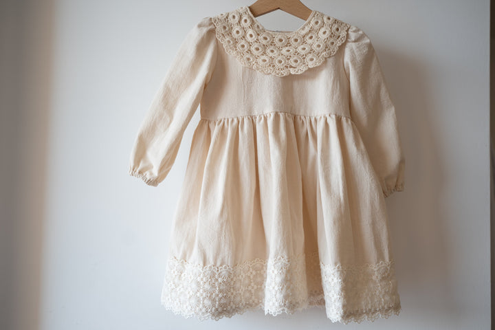 a dress hanging on a wall with a wooden hanger