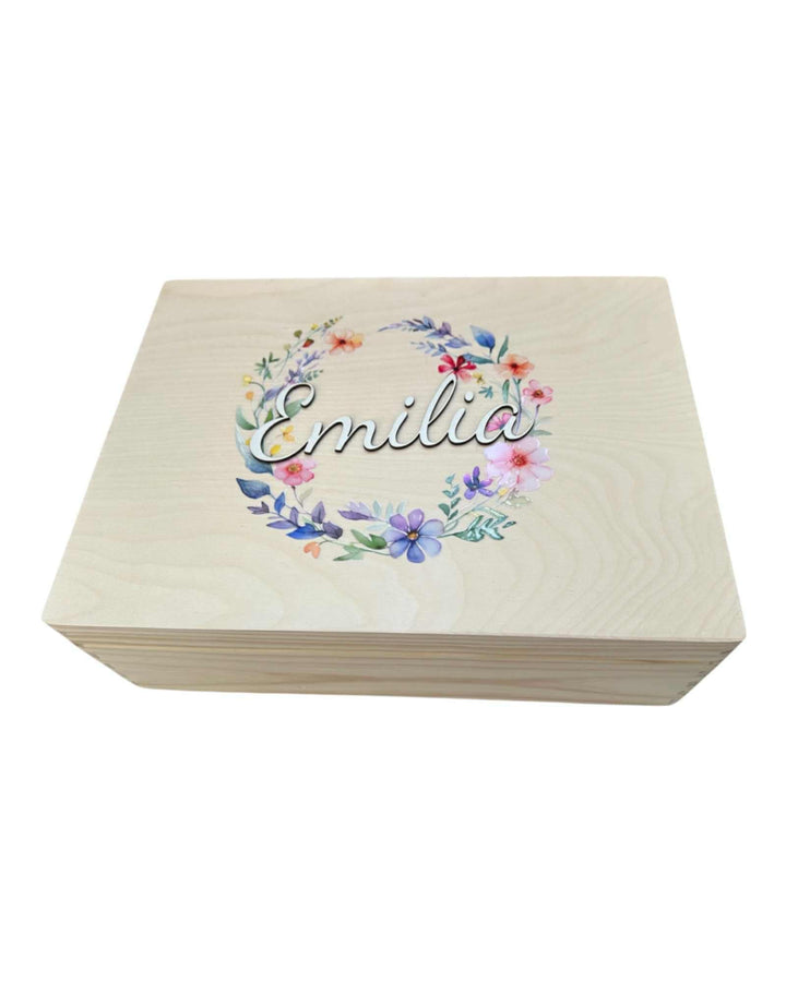 A wooden box with a floral wreath design featuring the name "Emilia" on it.