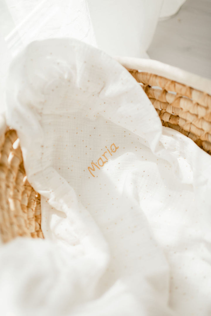 A white cloth with the name "Marie" printed on it, placed in a woven basket.