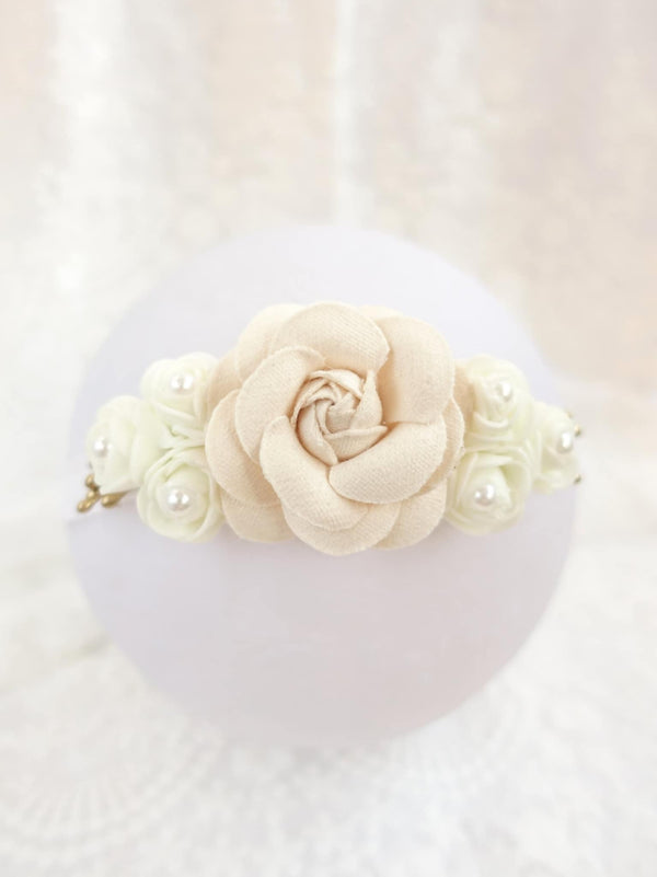 A white flower with a large center bloom is the focal point of the image, surrounded by smaller white flowers and pearls.