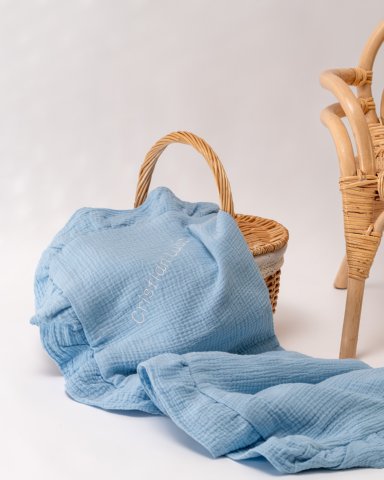 a blue blanket sitting next to a wicker chair