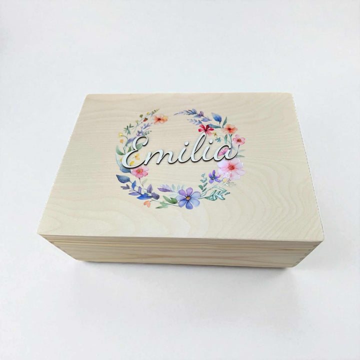 A wooden box with a floral wreath design and the name "Emilia" printed on it.