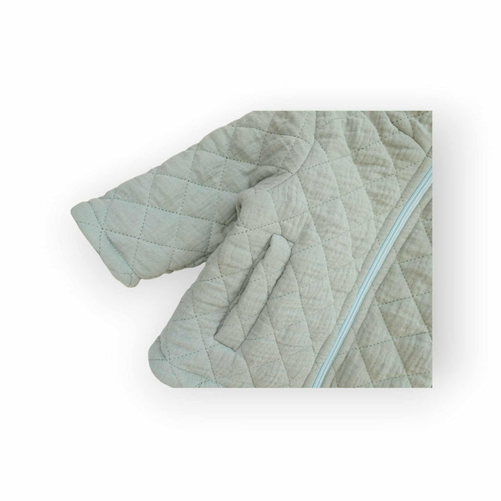 A close-up view of a light green quilted jacket with a zipper.