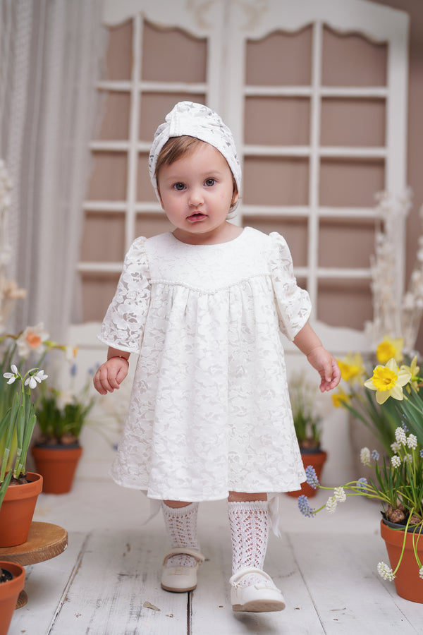 a little girl in a white dress and white socks