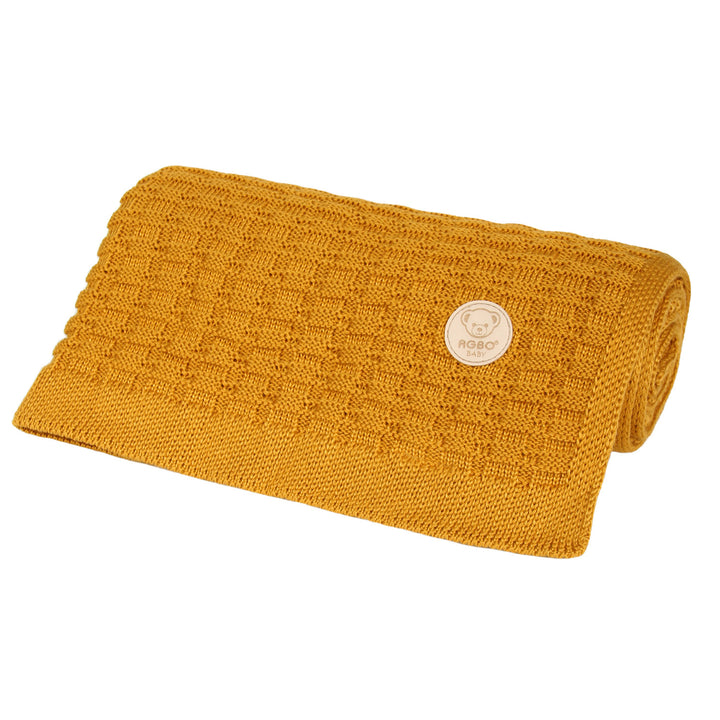 A yellow knitted blanket with a small white label on it.