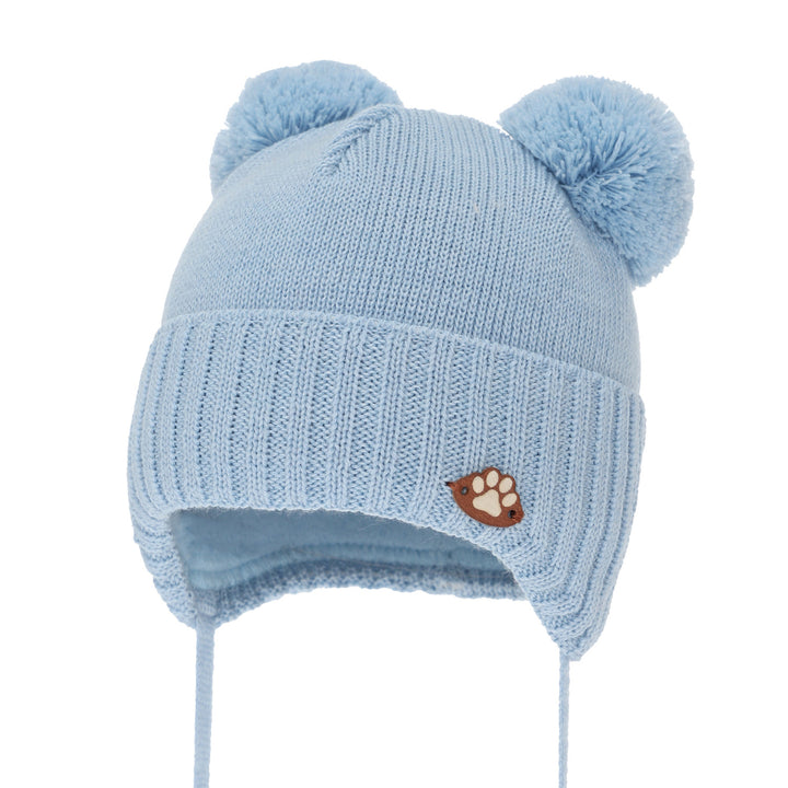 A light blue knitted hat with pom poms on the ears and a small brown paw print patch on the front.