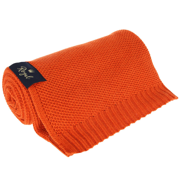An orange knitted scarf with a label attached to it.