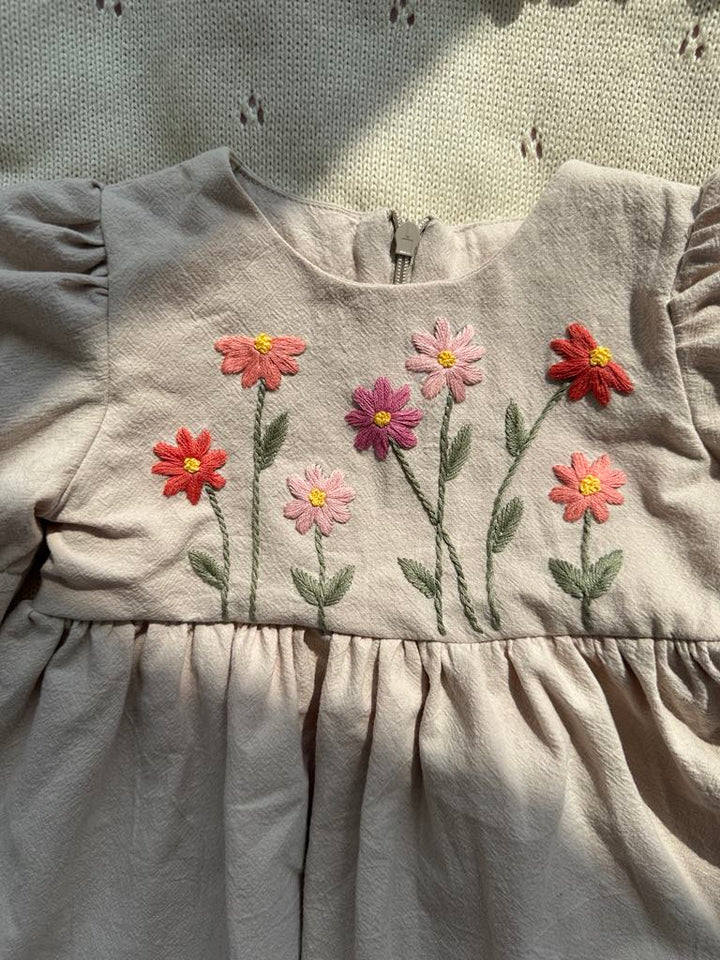 A beige dress with a floral embroidered design on the front.