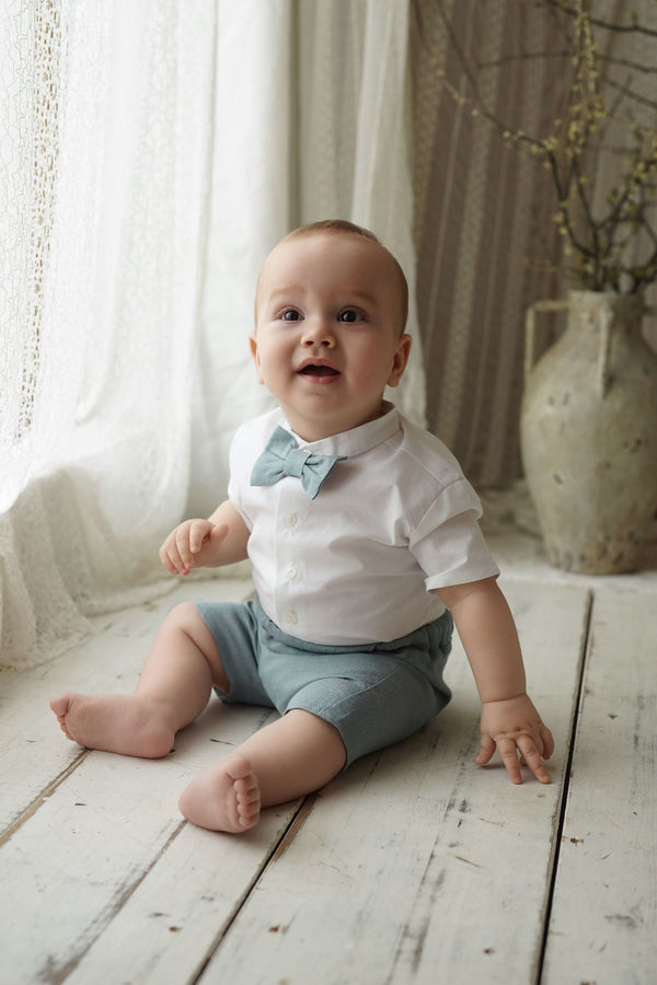 a baby sitting on the floor wearing a bow tie