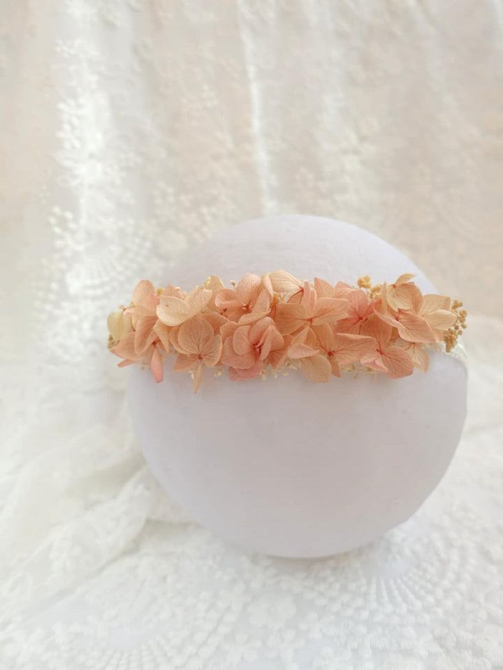 A white flower arrangement with delicate pink and peach-colored flowers is displayed on a white lace background.