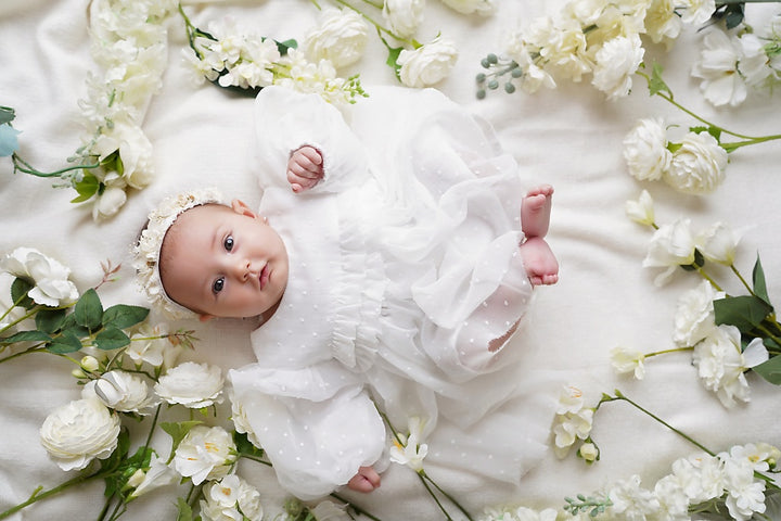 a baby laying on a bed of flowers