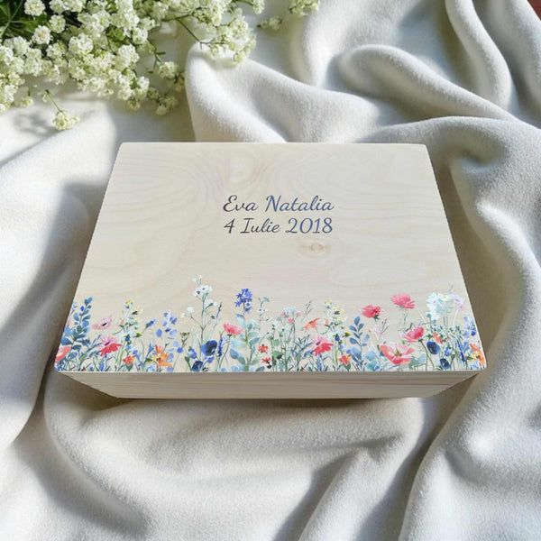 A wooden box with a floral design and the text " Eva Natalie 4 July 2018" printed on it, placed on a white cloth.