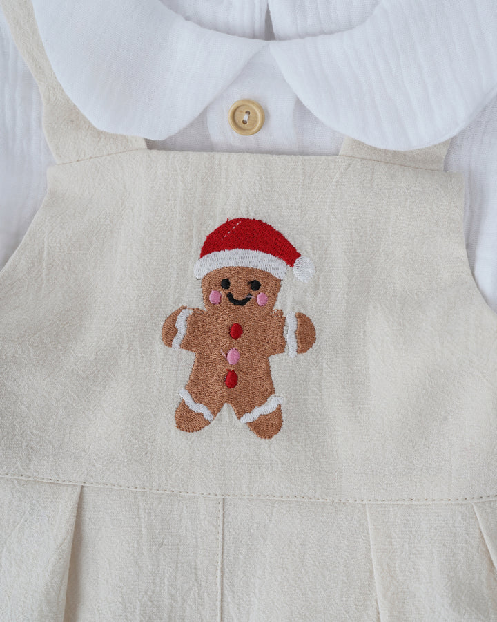 A close-up view of a white dress with a red and white gingerbread man embroidered on it.