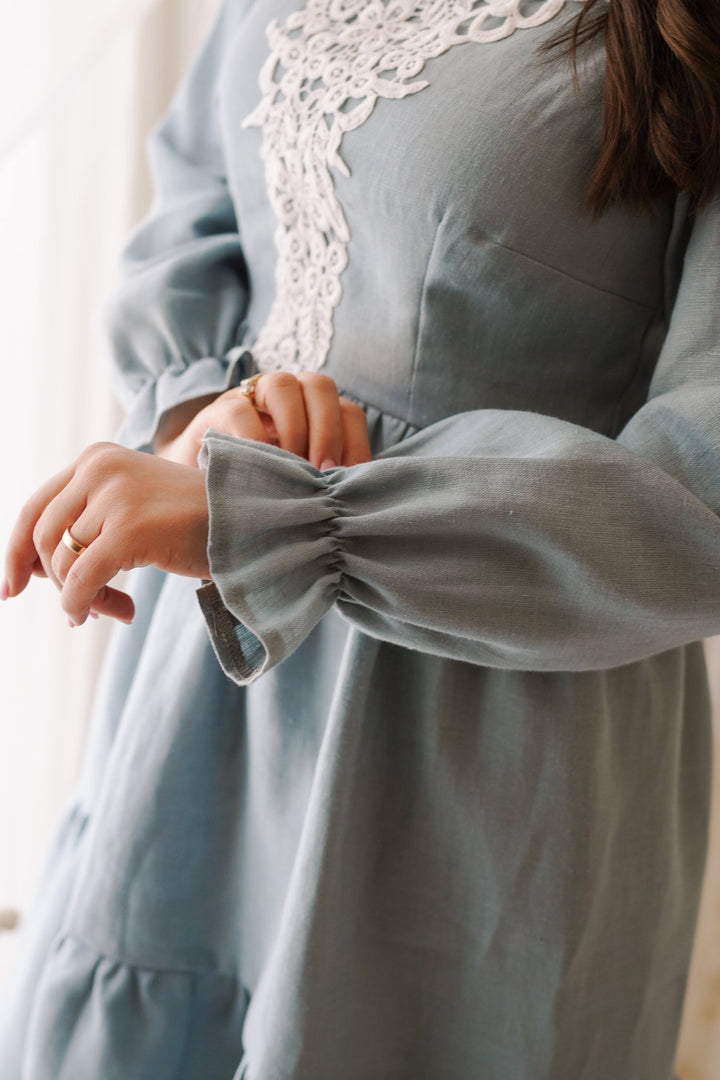 a woman wearing a blue dress with a white lace collar