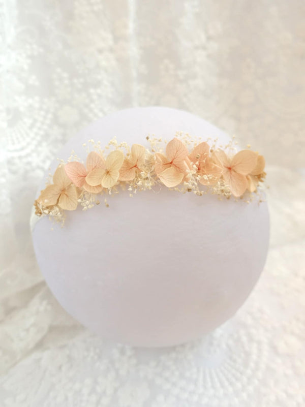 A white flower arrangement with delicate pink and white flowers is displayed on a white lace background.