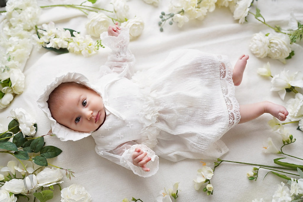 a baby laying on a bed of white flowers