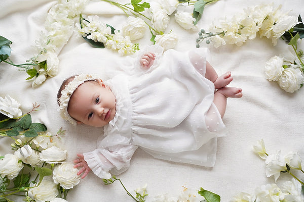 a baby laying on a bed of white flowers