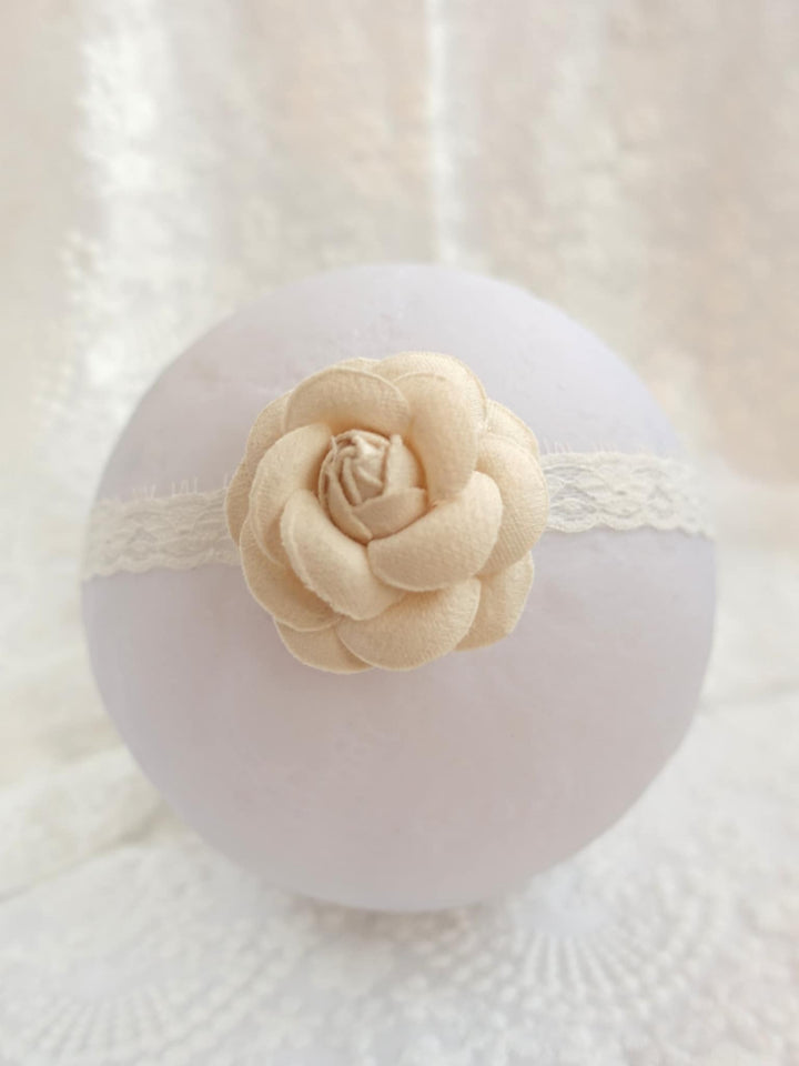 A white, round object with a delicate white lace trim around the edge, featuring a single light-colored flower as the focal point.